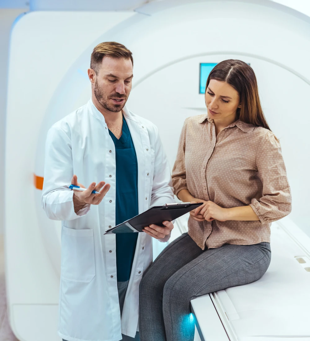Médico de Clínica Bupa Santiago revisando resultados con una paciente junto a un resonador